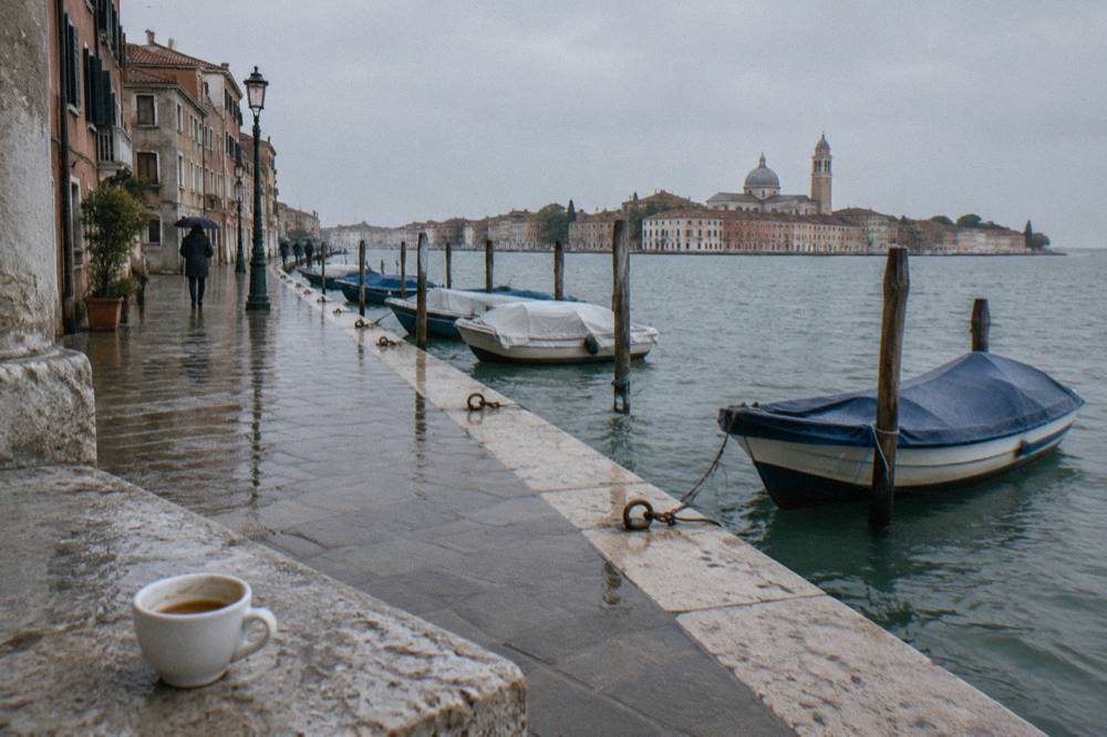 A Venice canal intersection with moored boats and faded plaster facades