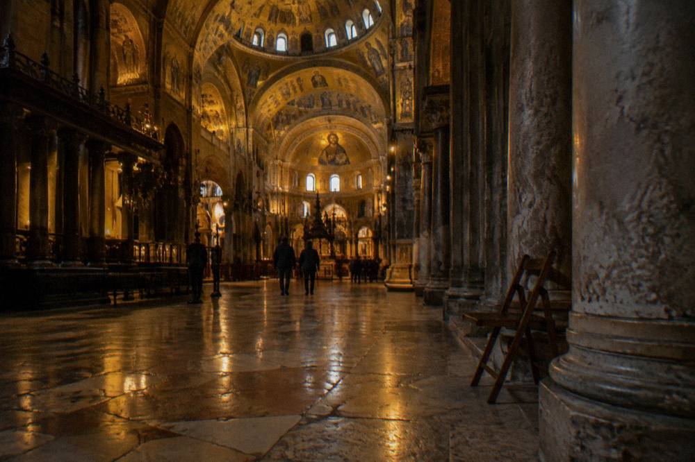 The golden mosaic interior of St Mark's Basilica glowing under low light