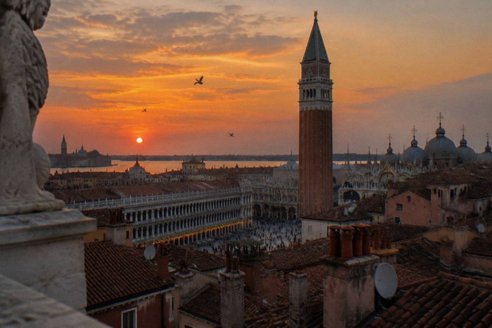 Campanile of St Mark's rising above the rooftops and chimneys of Venice at dusk