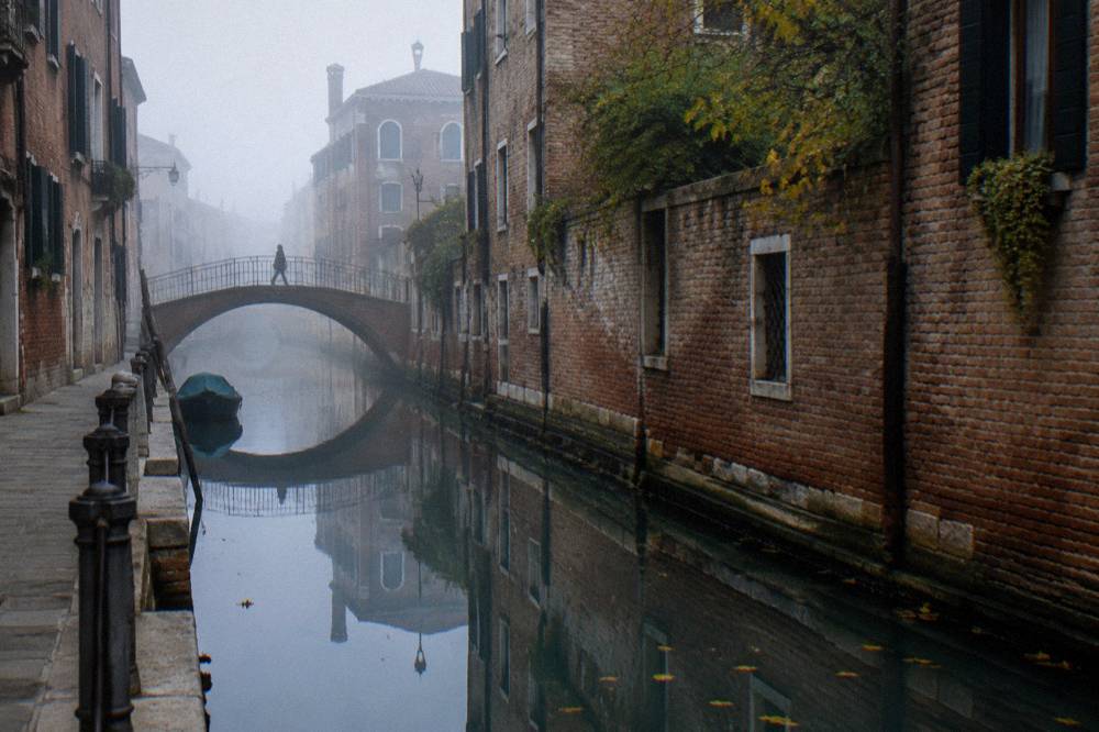 A narrow Cannaregio canal reflecting old brick buildings in still water