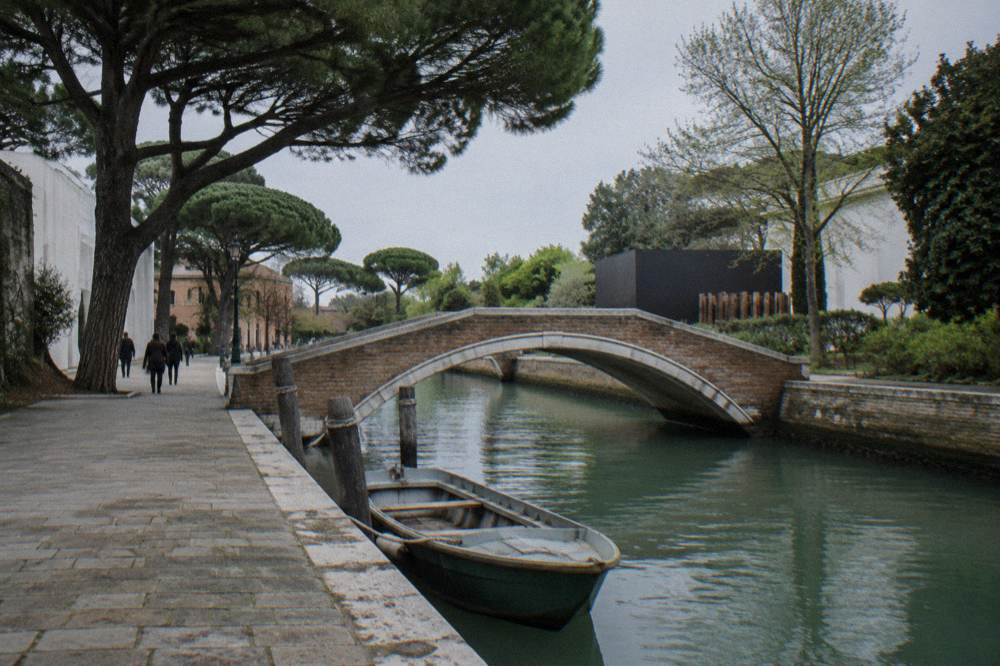 A quiet fondamenta in Castello with a stone bridge over a green canal