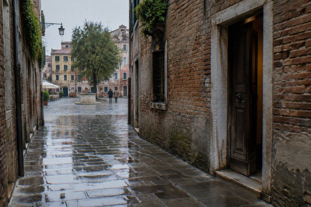A narrow Venice calle with worn stone paving and old brick walls