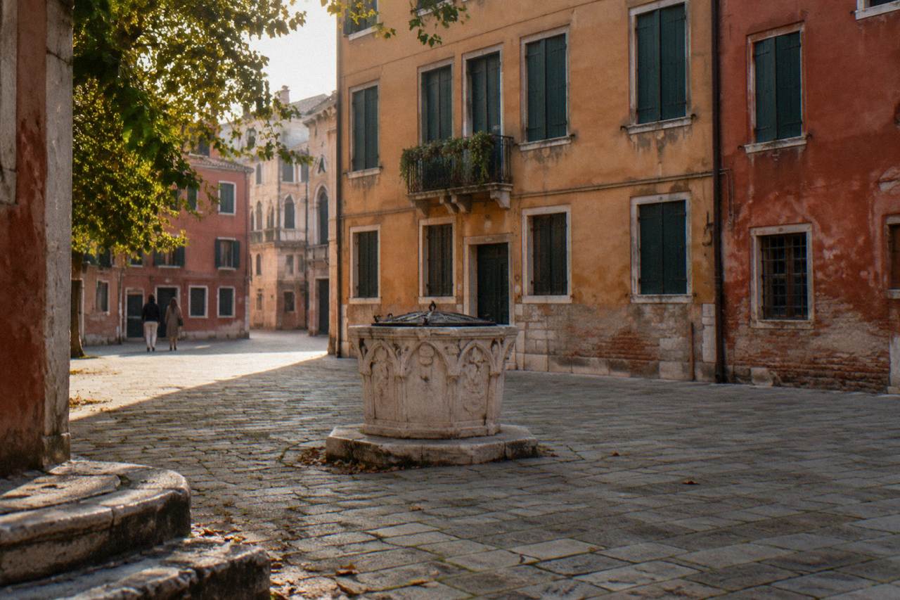 A quiet Venice campiello with a stone well head and shuttered facades