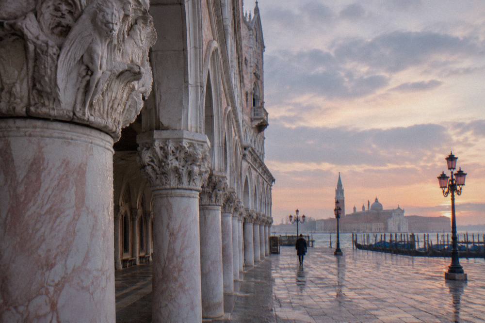 Pink and white stone arcades of the Doge's Palace seen from the lagoon waterfront