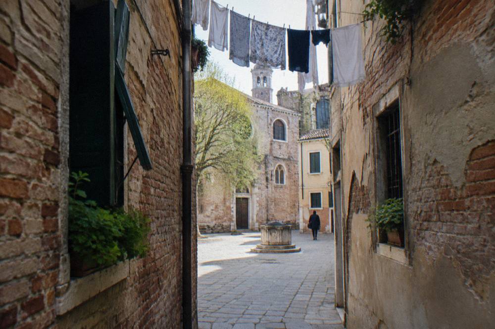 Narrow Venice alley with laundry above and worn brick walls