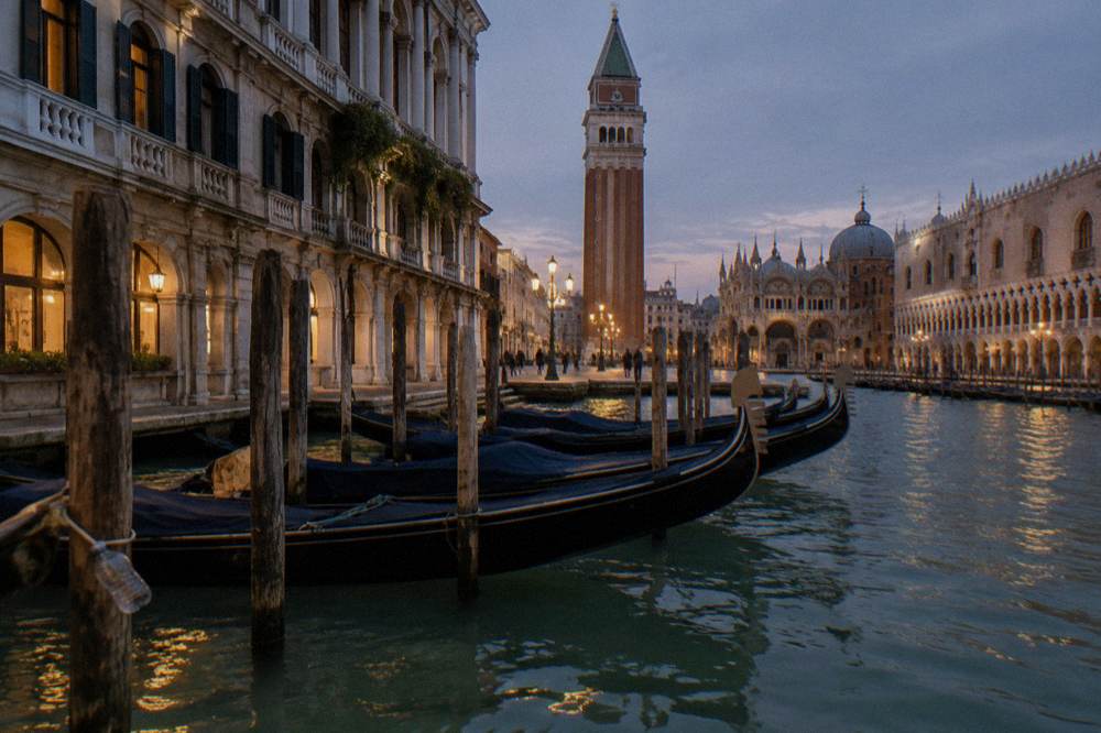 Gondolas moored along a Venice canal at dusk with lit windows