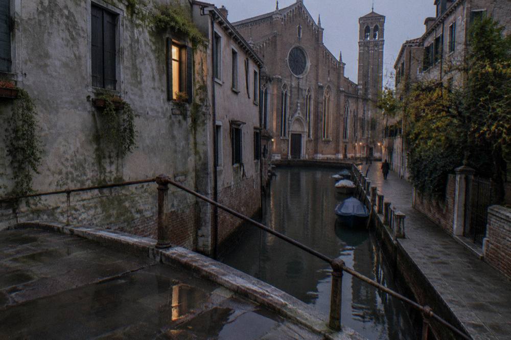 Narrow Venetian canal with a small bridge and weathered walls