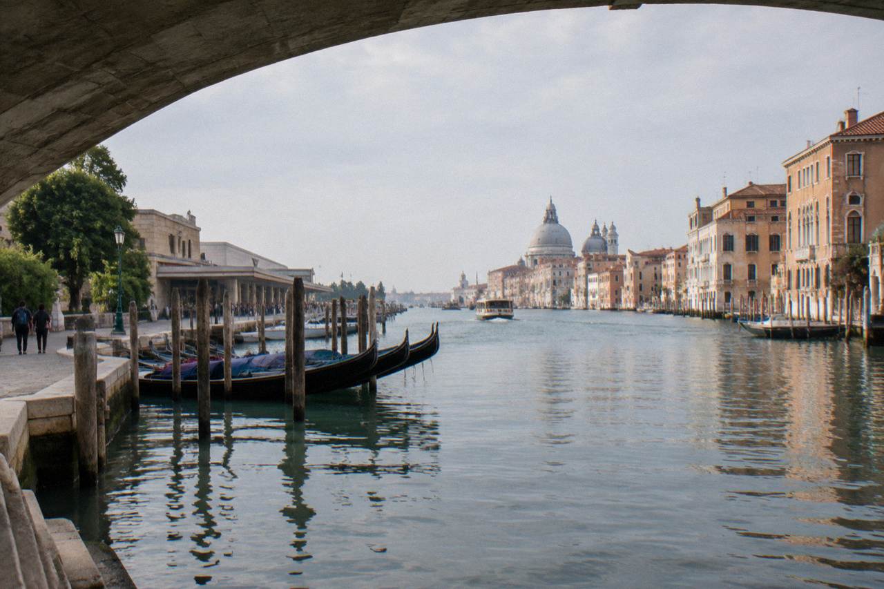 Quiet Venice canal with moored boats and sunlit facades