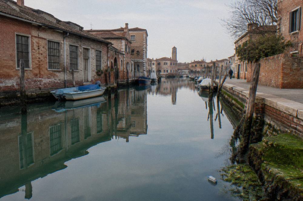 A quiet canal in Murano with brick buildings reflected in still water