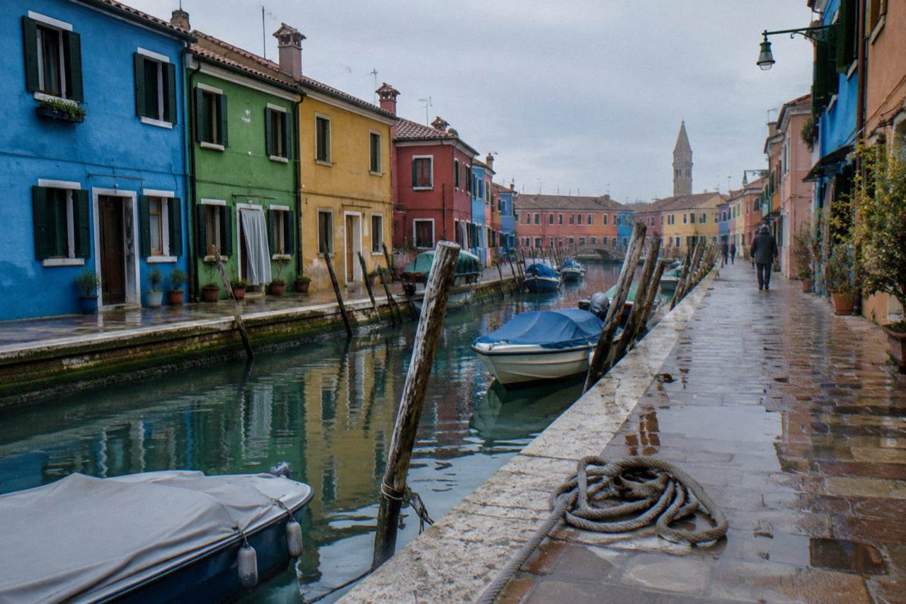 Colourful fishermen's houses along a canal in Burano, with moored boats