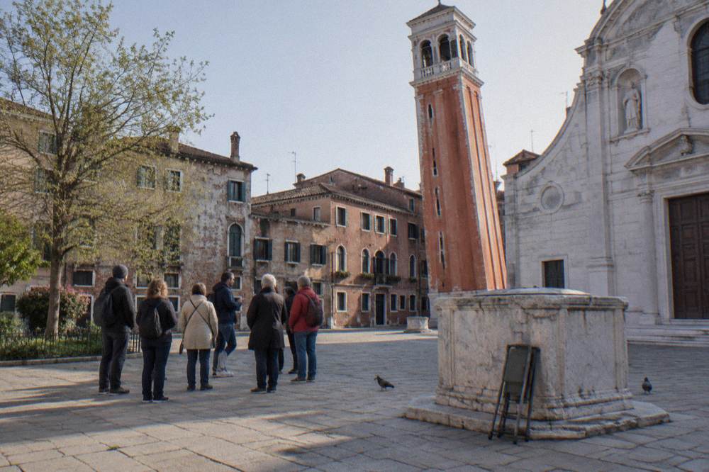 Narrow Venetian street with a small group walking beside old brick buildings