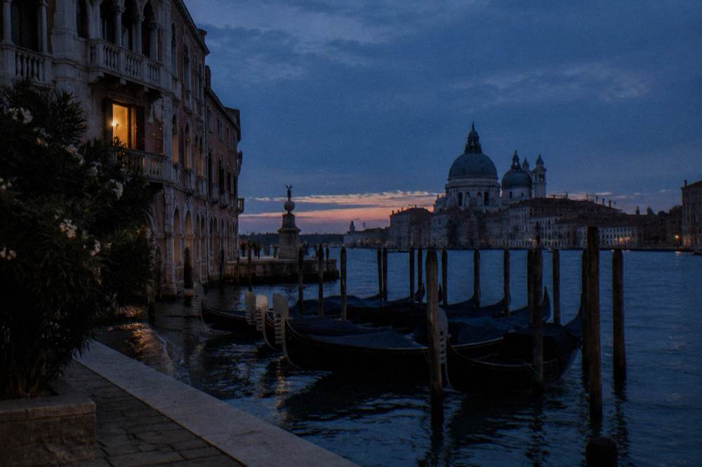 Grand Canal in Venice at dusk with silhouetted palazzos and gondolas moored along the water