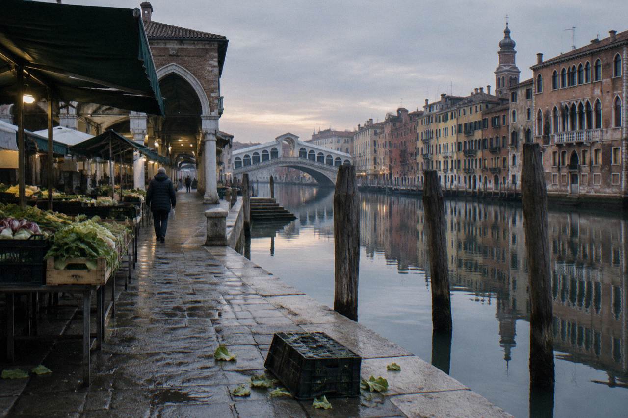 Quiet canal in Venice with moored boats and old brick facades reflected in still water