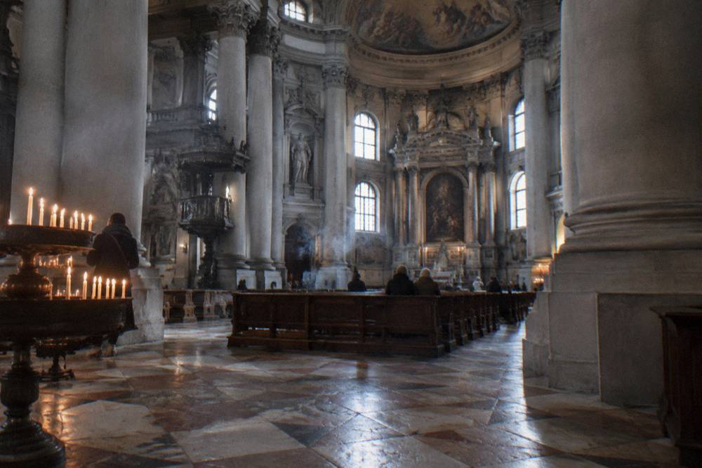 Interior of a large Venetian gothic church with tall columns and painted ceiling