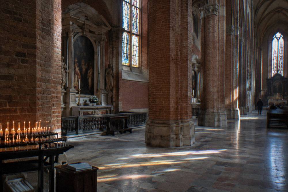 Gothic brick church interior with tall columns and side altars