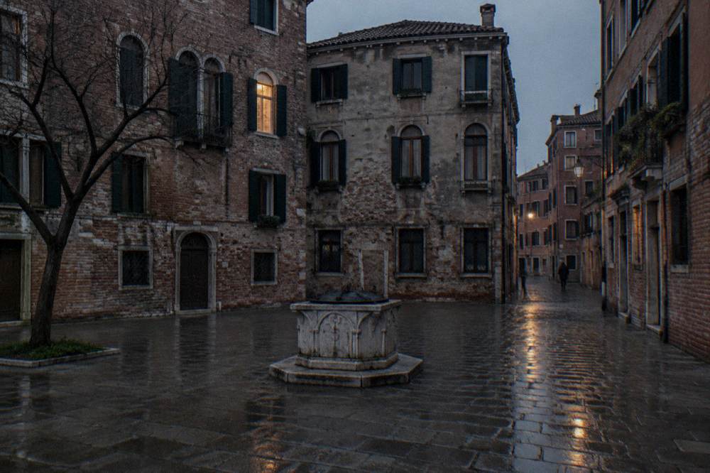 Quiet Venice campo enclosed by old brick buildings with an empty wellhead
