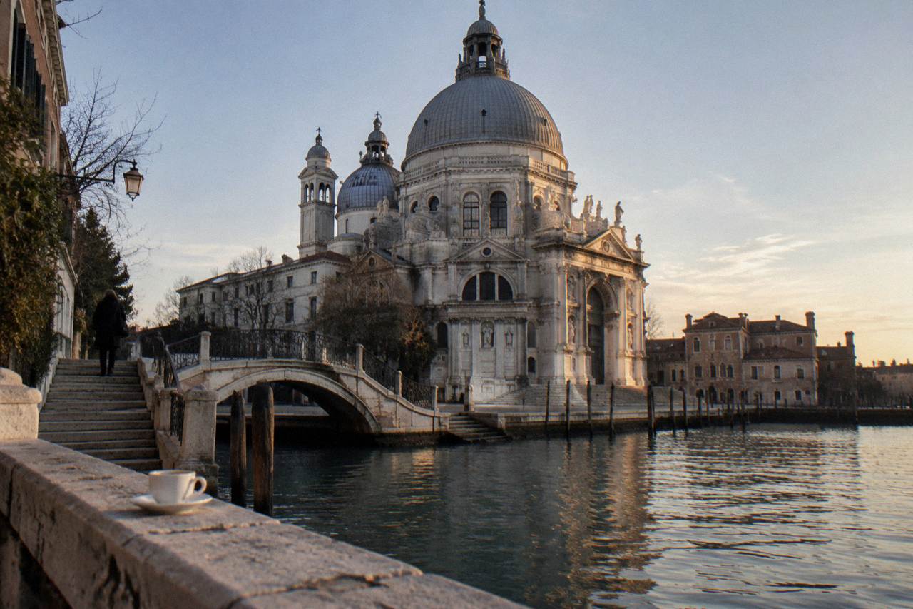 Stone church facade beside a narrow Venice canal with a small bridge