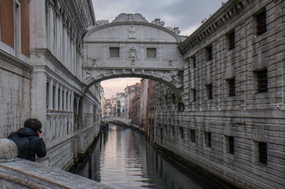 Gondolas moored on a narrow canal beside a stone bridge in Venice