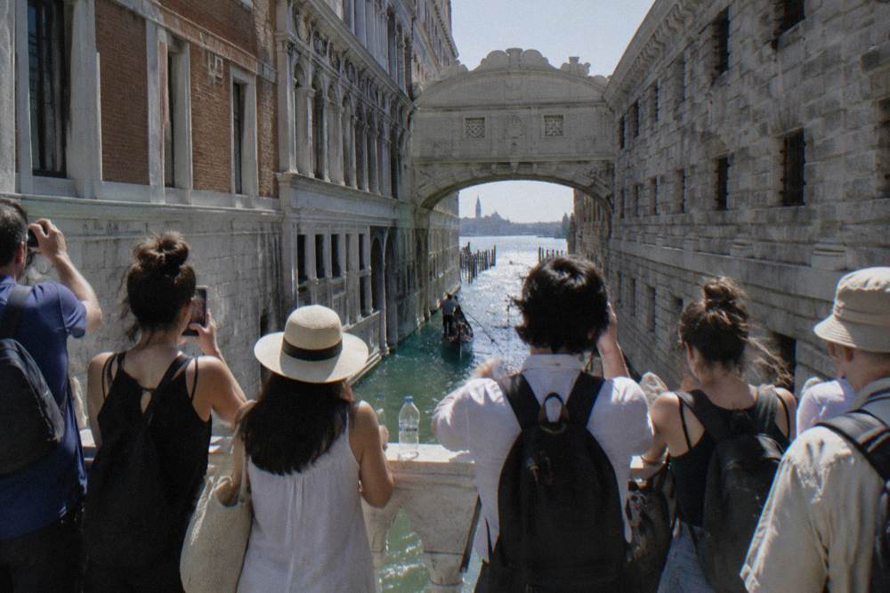 Narrow Venice street with old plastered buildings and a small canal crossing ahead