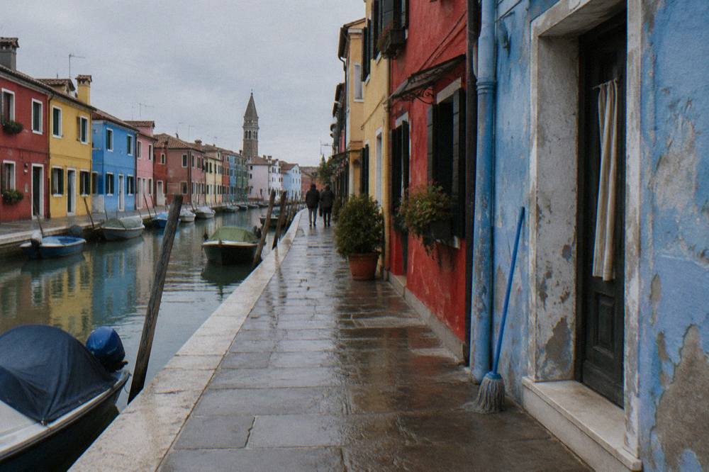A quiet Burano street with small houses painted in red, yellow and blue beside a narrow canal