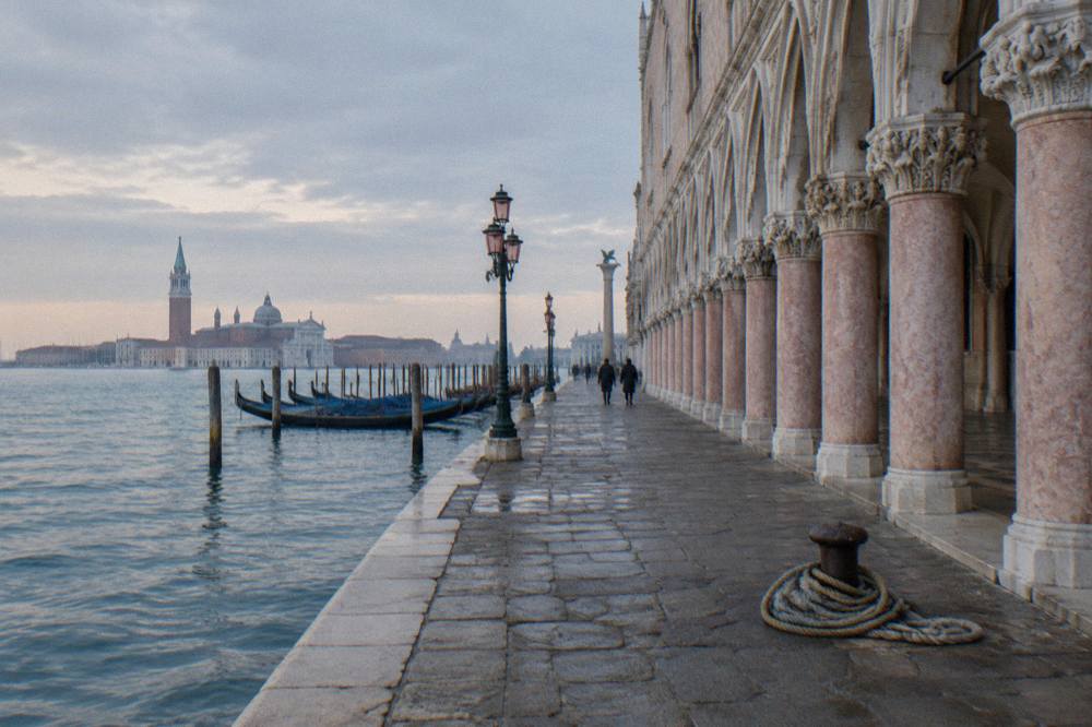 The pink and white gothic arcade of the Doge's Palace seen from the lagoon waterfront