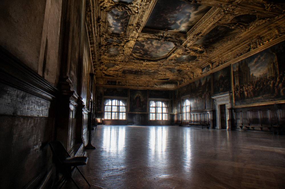 Ornate gilded ceiling and large oil paintings inside a grand council hall