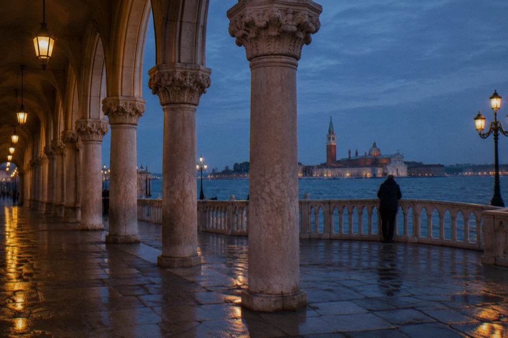 The arcade columns of the Doge's Palace along the waterside promenade at dusk