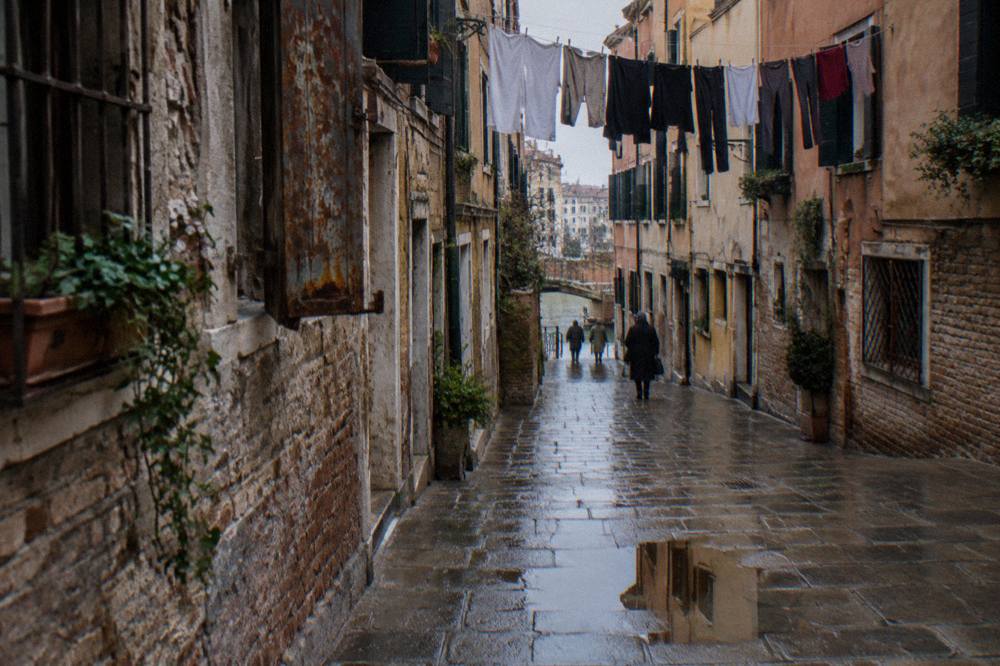 A narrow Venice alley with worn stone paving and laundry hanging above