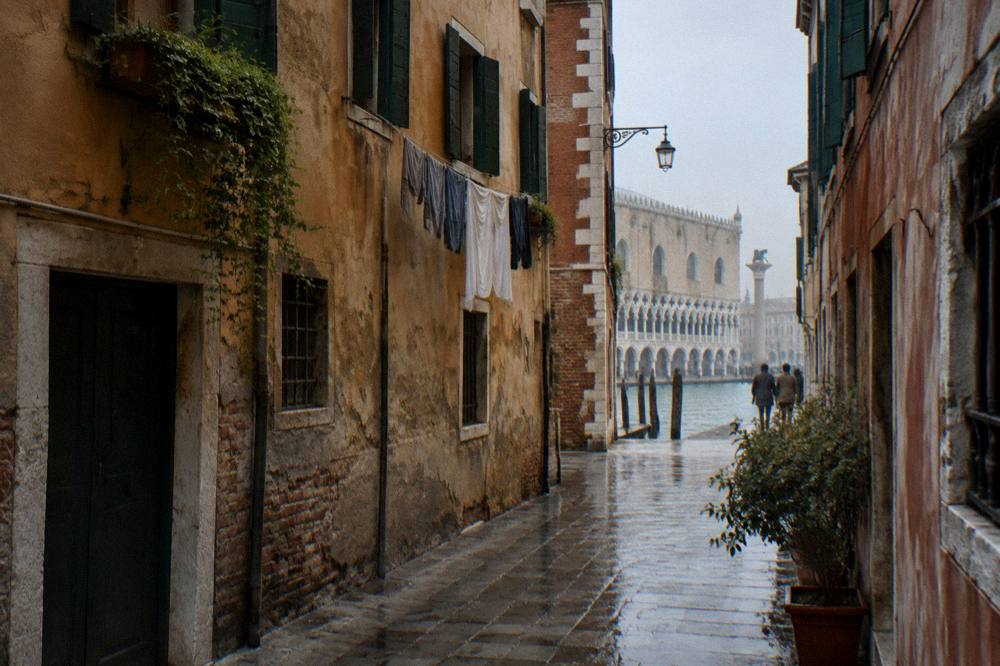 A quiet residential Venice lane with green shutters and a canal glimpsed at the end