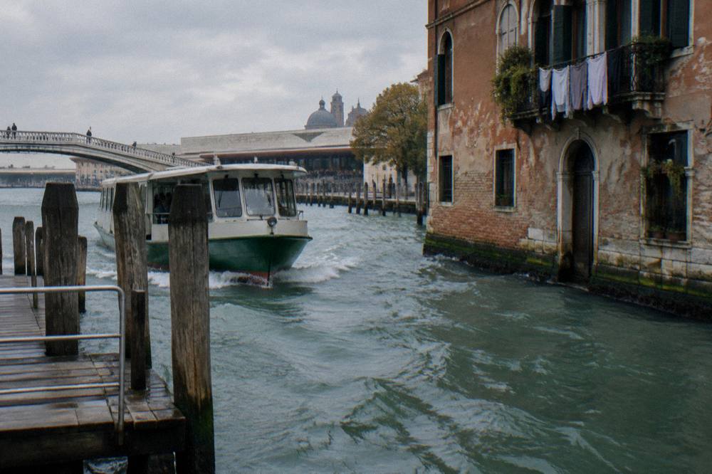 Vaporetto boat approaching a wooden landing stage on a Venice canal