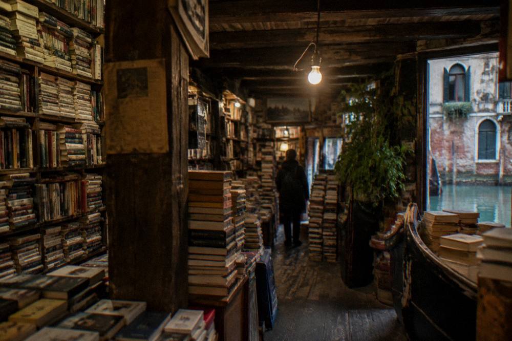 Shelves of stacked books inside a dimly lit Venetian bookshop