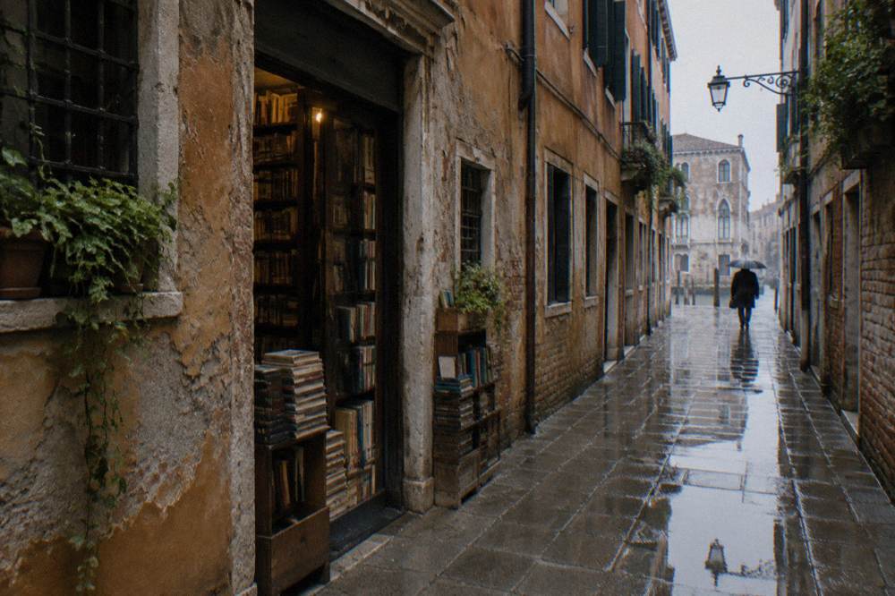 A narrow Venice alley with a small bookshop entrance between old buildings