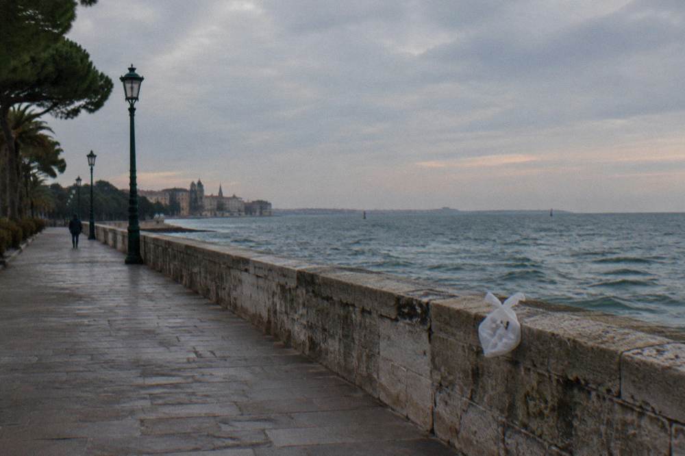 An empty seafront promenade in soft autumn light with the stone seawall running to the horizon