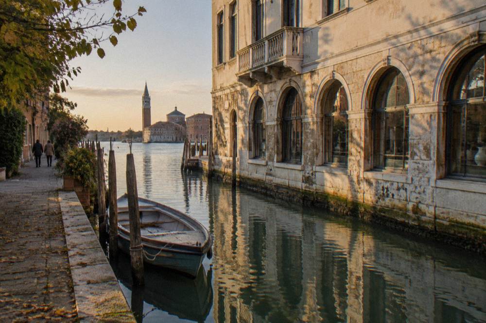 The stone facade of a museum building on a Murano canal seen from across the water