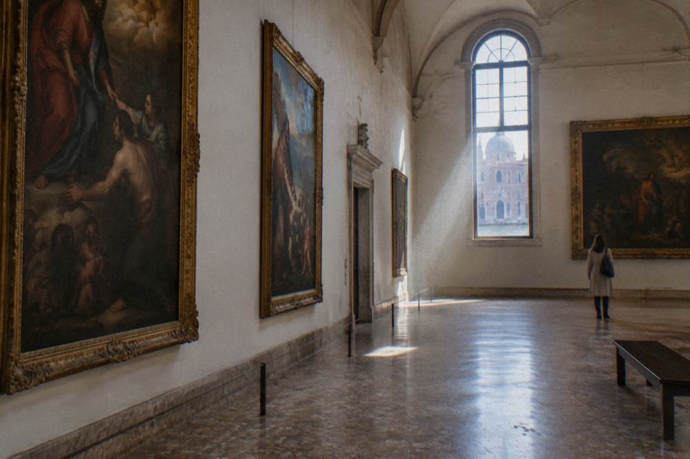 A museum hall with large old paintings on the walls and a stone floor