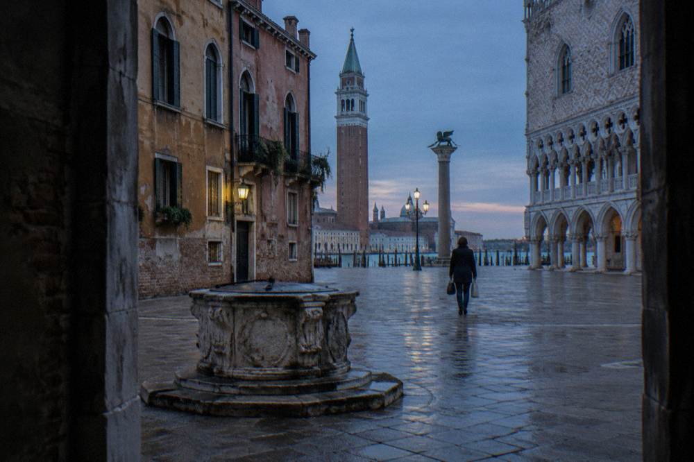 A quiet campo near the Rialto with stone well heads and faded plaster facades in morning light