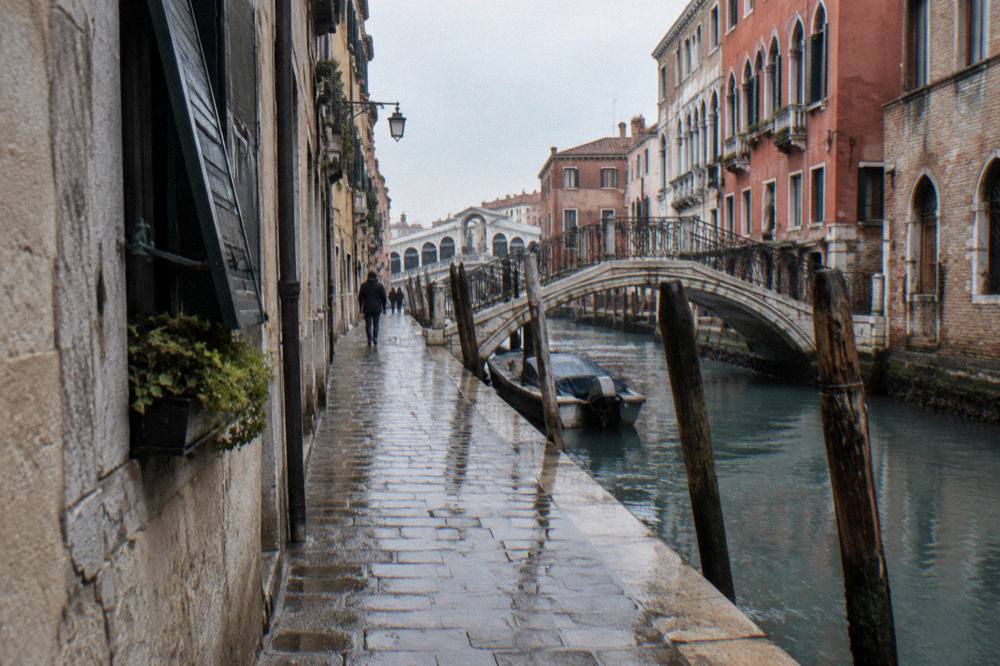 A canal-side street leading away from the Rialto with mooring poles and bridged side canals