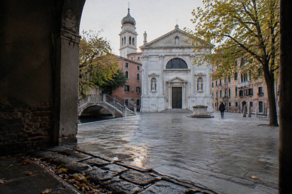 A quiet Venetian campo with a church facade and canal bridge near the San Marco district