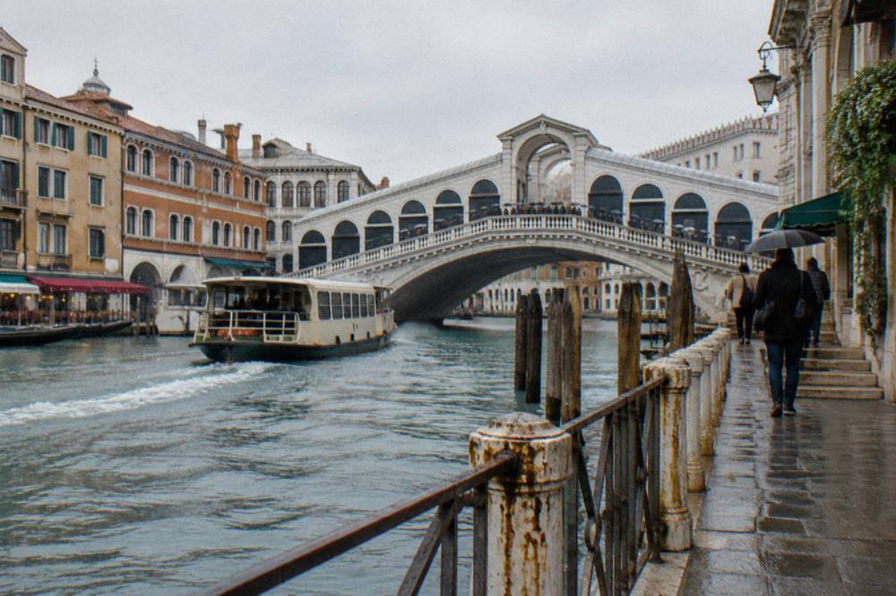 Crowd of visitors crossing a small bridge over a Venice canal in daylight