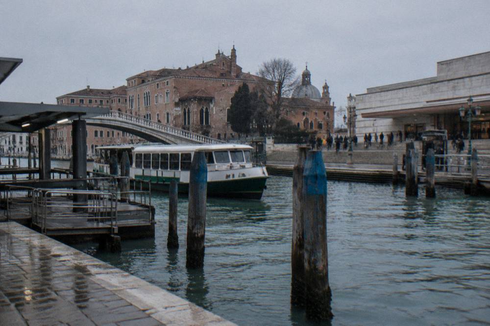 Ferry dock on a Venice canal with mooring poles and brick facades