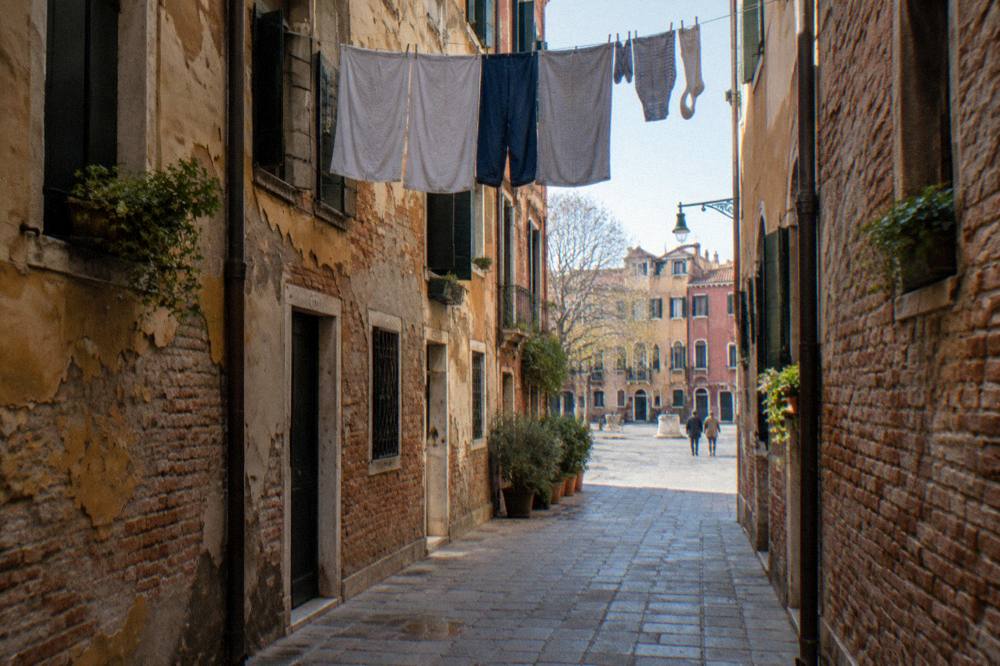 Narrow Venice alleyway with laundry overhead and worn plaster walls