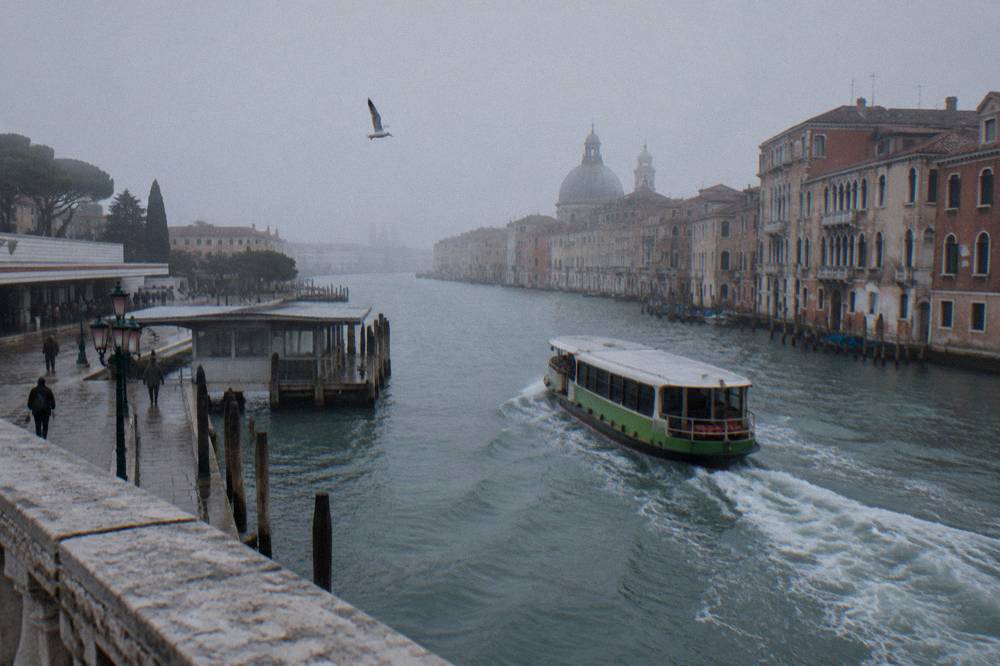 A vaporetto water bus moving along the Grand Canal with palazzi behind it